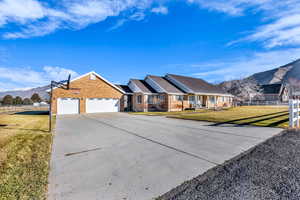 Ranch-style home featuring a mountain view, a garage, brick siding, and driveway