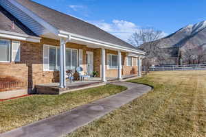 Rear view of property with a porch, brick siding, roof with shingles, and a mountain view