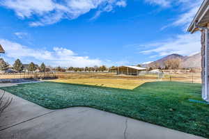 View of yard with a patio area, a view of countryside, a mountain view, and an outbuilding