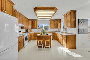 Kitchen with white appliances, light countertops, wood finish cabinetry, and light floors