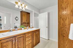 Bathroom with double vanity, light flooring, and a chandelier