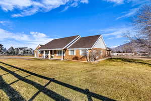 View of front of home with covered porch, roof with shingles, and brick siding