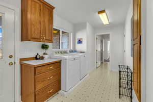 Laundry area with light flooring, washing machine and clothes dryer, and cabinet space