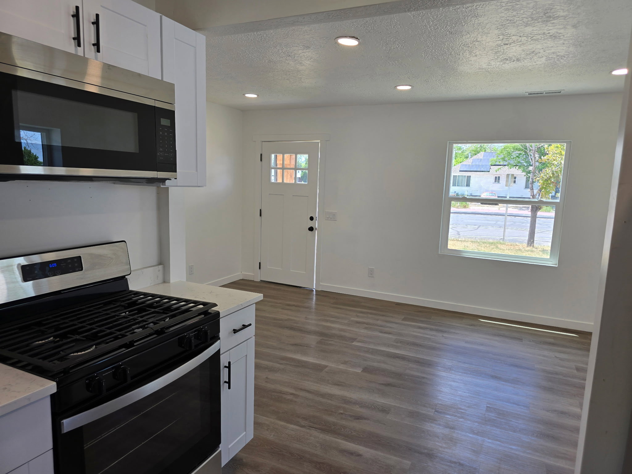 Kitchen with stainless steel appliances, white cabinets, recessed lighting, a textured ceiling, and dark wood-type flooring