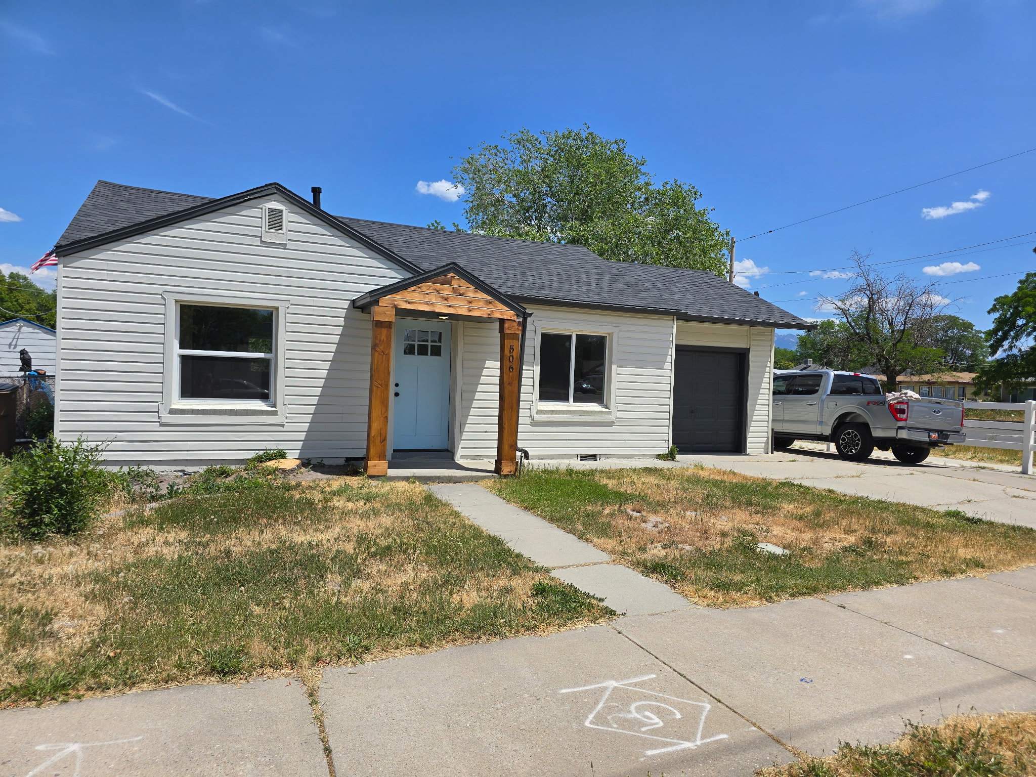 View of front of home featuring roof with shingles, a front yard, a garage, and driveway
