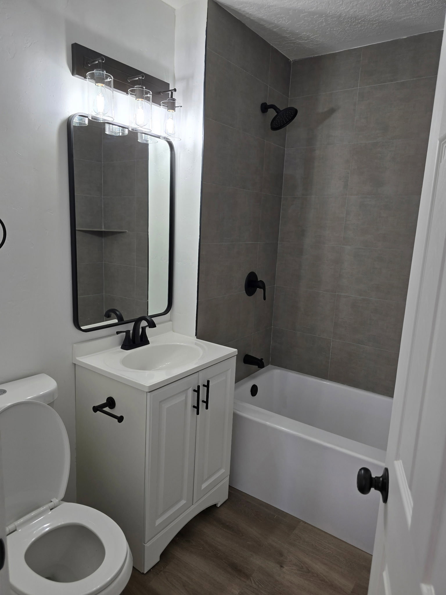 Full bath featuring vanity, dark wood-style floors, shower / bathtub combination, and a textured ceiling