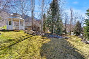 View of green lawn featuring a gazebo and a deck with mountain view