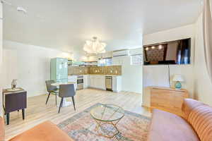 Living room with light wood-style flooring and a wall mounted mini split