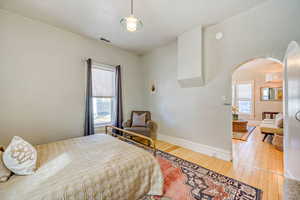 Bedroom featuring arched walkways and light wood-style flooring