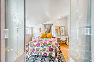 Bedroom featuring light wood-style floors and vaulted ceiling