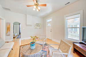 Living area featuring arched walkways, a ceiling fan, and light wood-style flooring