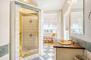 Bathroom featuring vanity, a shower stall, ensuite bath, and tile walls