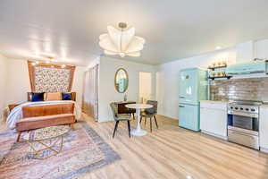 Bedroom featuring light wood finished floors and freestanding refrigerator