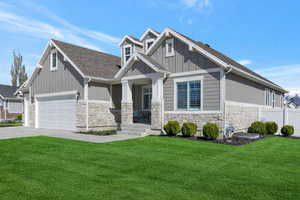 Craftsman-style home with stone siding, a front lawn, driveway, and board and batten siding