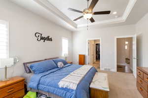 Bedroom featuring a walk in closet, ceiling fan, and light carpet