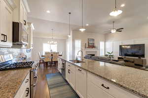 Kitchen featuring white cabinets, stainless steel appliances, dark wood-type flooring, and light stone countertops