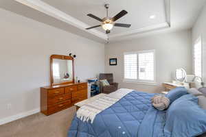 Bedroom with carpet floors, multiple windows, ceiling fan, a raised ceiling, and recessed lighting