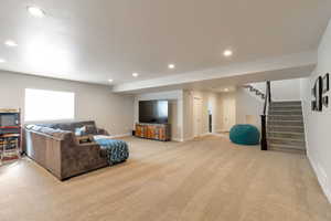 Living area with light carpet and recessed lighting