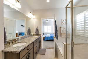 Ensuite bathroom with double vanity, a stall shower, light carpet, light tile patterned floors, and ceiling fan