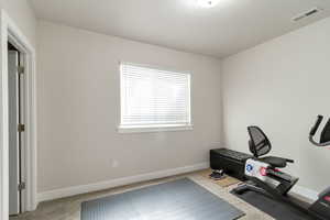 Exercise room with light colored carpet and baseboards
