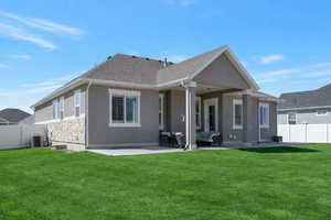 Back of house featuring a fenced backyard, a patio area, stucco siding, and stone siding