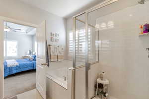 Full bath with carpet flooring, a shower stall, ensuite bath, a garden tub, and a ceiling fan