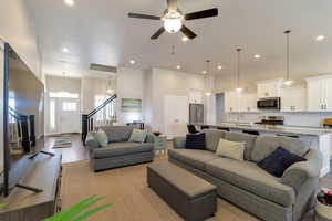 Living room with light wood-style flooring, a high ceiling, a ceiling fan, and recessed lighting
