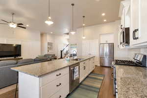 Kitchen featuring white cabinetry, open floor plan, and stainless steel appliances