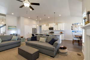 Living area featuring suspended lighting, a ceiling fan, dark wood finished floors, and a high ceiling