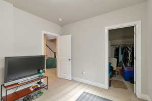 Bedroom with light colored carpet and a walk in closet