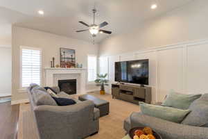 Living area featuring a decorative wall, ceiling fan, a glass covered fireplace, and recessed lighting