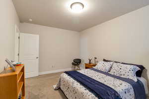 Bedroom featuring light carpet and baseboards