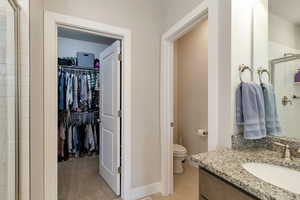 Bathroom with a stall shower, vanity, a spacious closet, and light colored carpet
