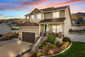 View of front facade featuring a shingled roof, a mountain view, concrete driveway, and board and batten siding