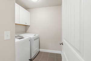 Laundry room with cabinet space, a textured ceiling, and independent washer and dryer