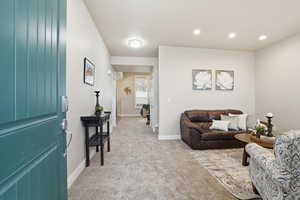Living area featuring light colored carpet and recessed lighting