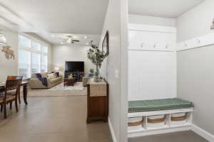 Mudroom with a ceiling fan and light tile patterned floors