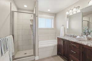 Full bathroom featuring double vanity, a bath, a stall shower, and recessed lighting