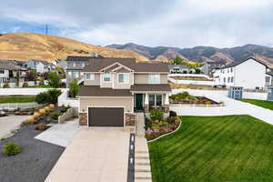 View of front facade with a residential view, a mountain view, concrete driveway, and stone siding