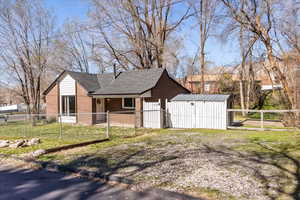View of home's exterior with a fenced front yard, a shingled roof, brick siding, a gate with plenty of parking!