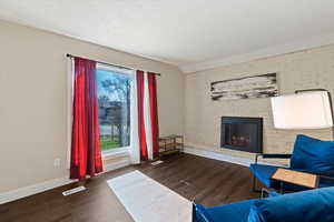 Living area with a fireplace insert, large picture window and brick wall.
