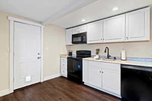 Kitchen featuring black appliances, white cabinetry, dark wood-style floors, recessed lighting, and light stone counters
