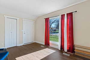 Foyer entrance featuring vaulted ceiling and dark wood-style floors