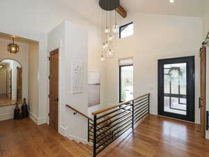 Foyer entrance with hardwood / wood-style flooring, arched walkways, a barn door, and lofted ceiling