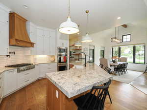 Kitchen with a breakfast bar, light wood-type flooring, a large island, stainless steel appliances, and two tone color scheme