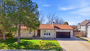 View of front of house featuring an attached garage, concrete driveway, and a chimney