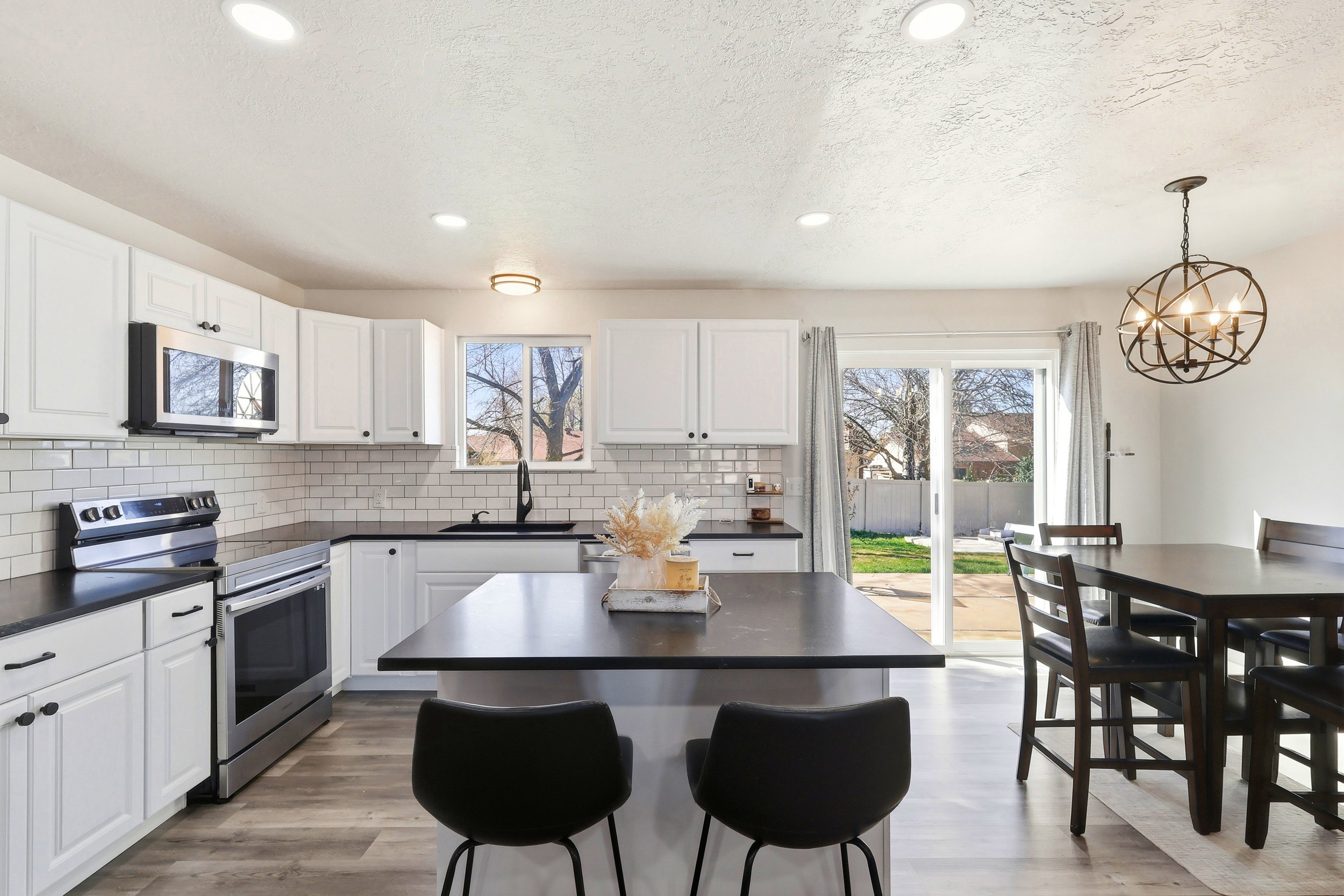 Kitchen featuring stainless steel appliances, white cabinets, light wood-type flooring, and a textured ceiling