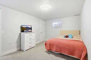 Bedroom with a textured ceiling and light colored carpet