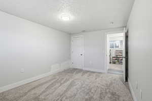 Unfurnished bedroom with a textured ceiling and light carpet