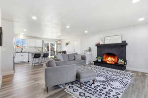 Living area featuring light wood-style flooring, a brick fireplace, and recessed lighting